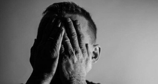 Sad man covering face with hands